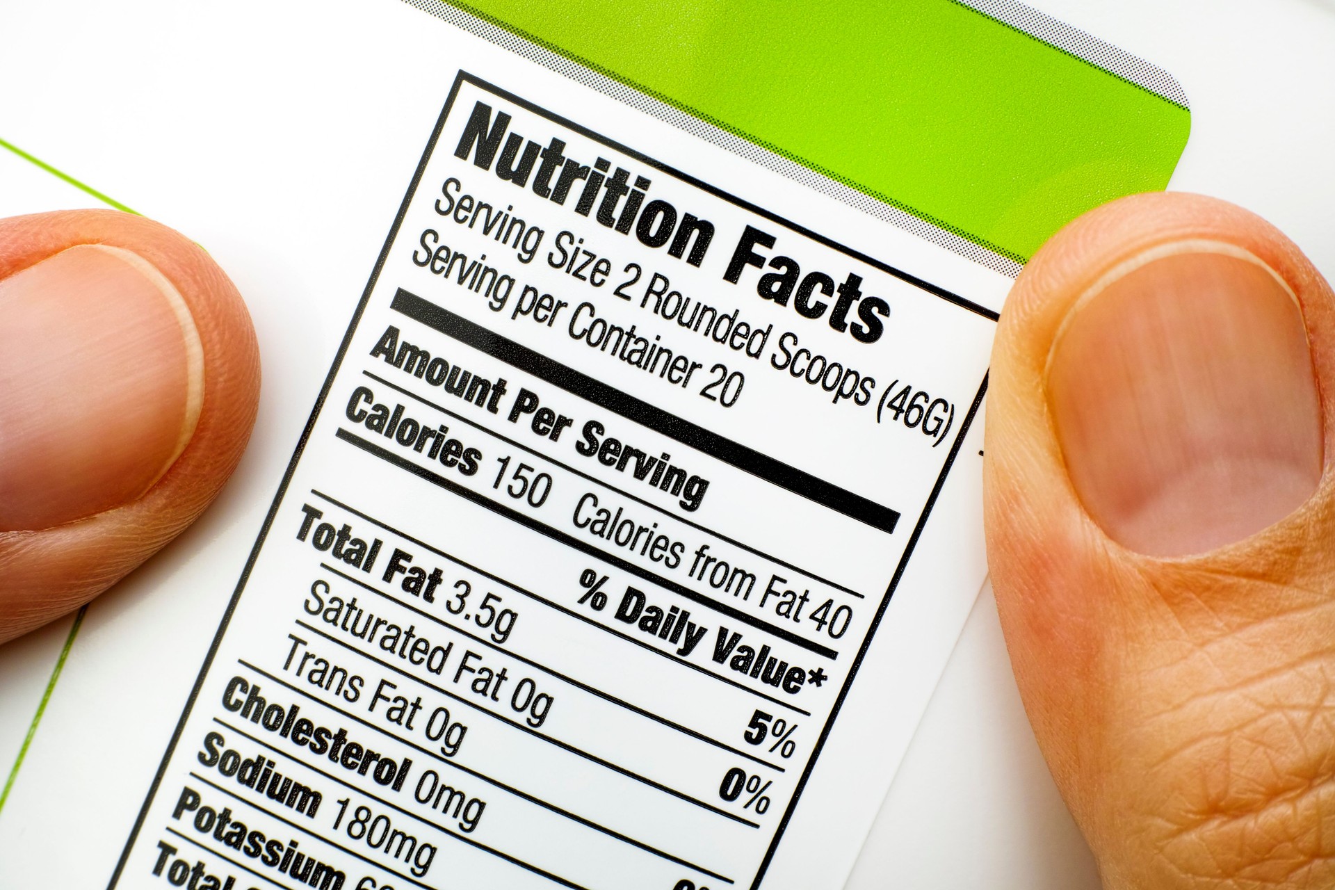 Woman fingers with protein jar. Reading nutrition facts